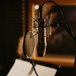 Close-up of a microphone and pop filter in a dimly lit recording studio, perfect for music production.
